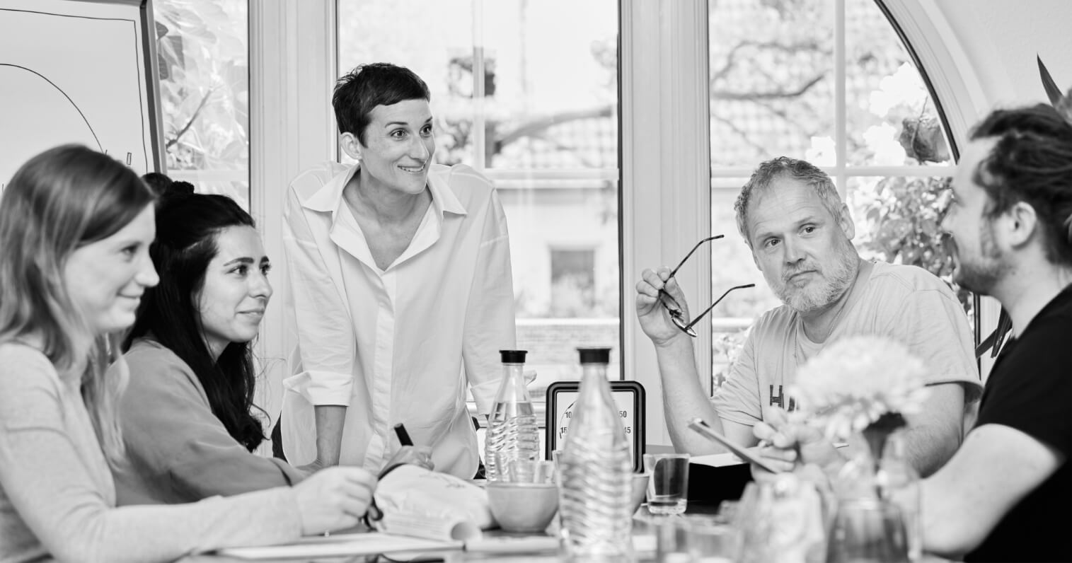 Helene mit vier Menschen an einem Tisch in einem Workshop